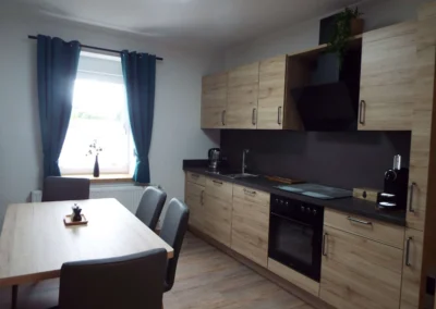 Moderne Küche einer Ferienunterkunft in Bolsdorf (bei Hillesheim) mit großem Esstisch und grauen Stühlen.